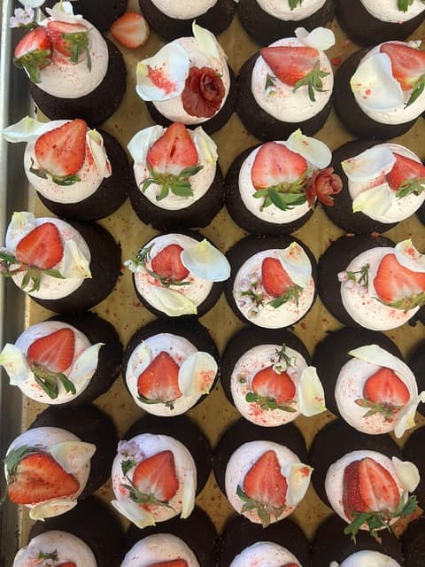 Chocolate cupcakes with strawberries and flower petals